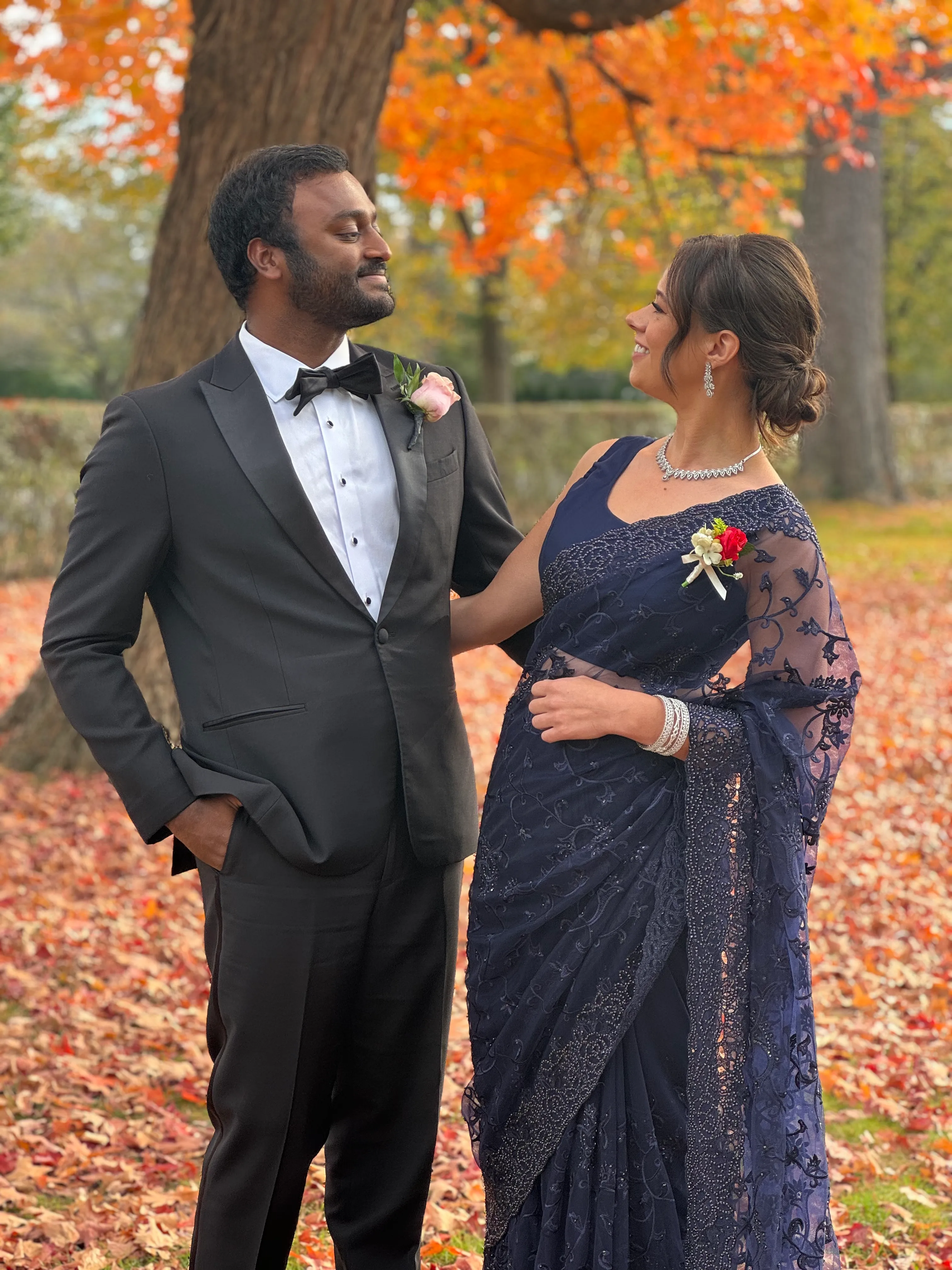Brianna and Ivan dressed formally among autumn leaves.