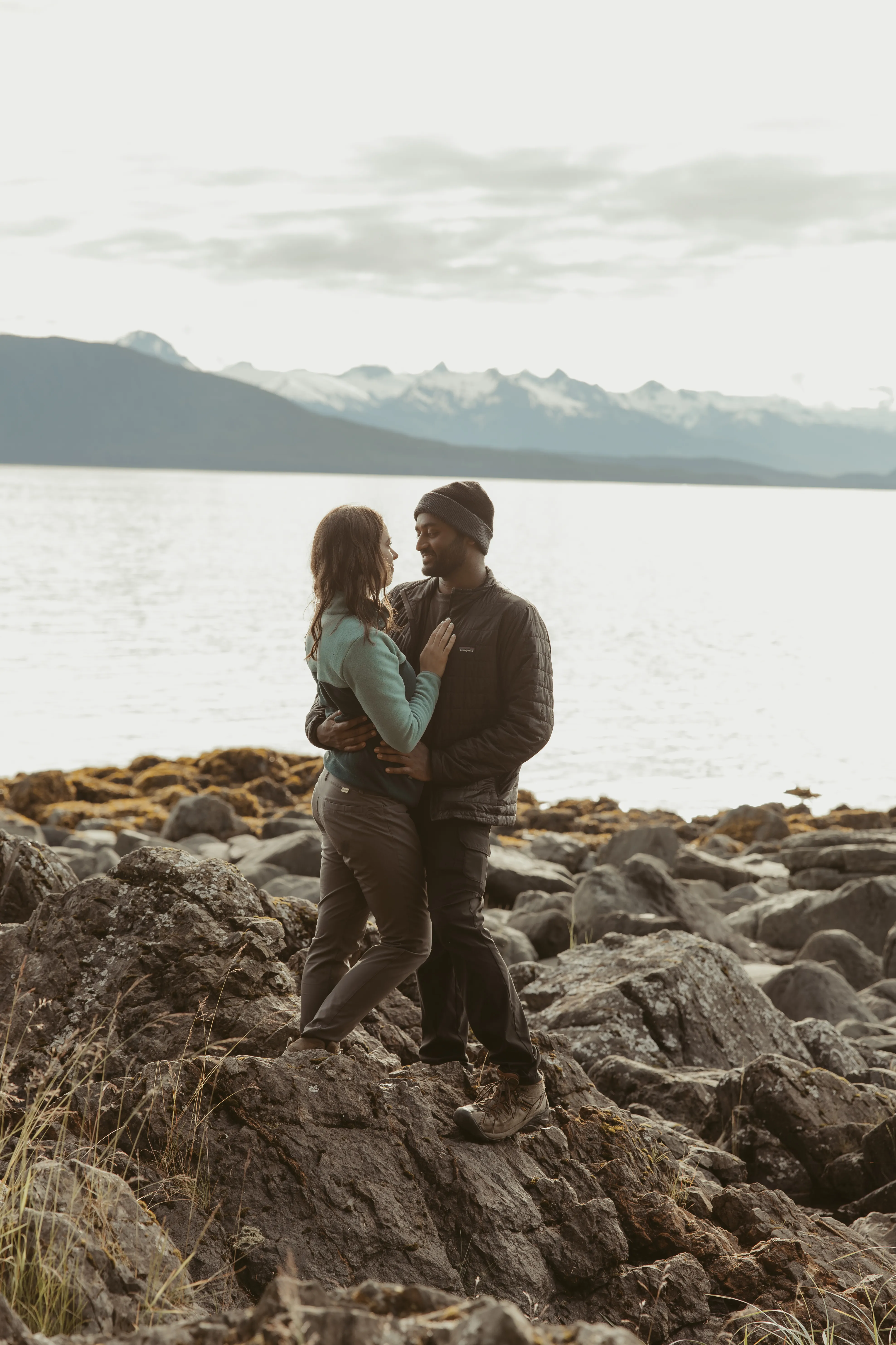 Brianna and Ivan sitting together and laughing by the coast.