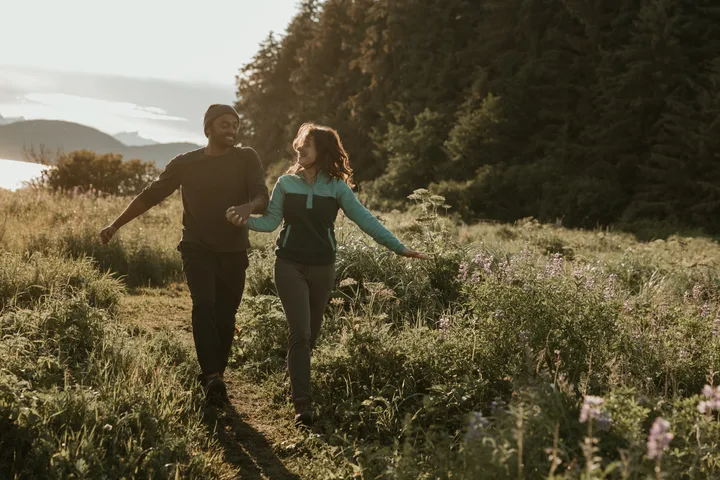 Brianna and Ivan walking through a sunlit meadow trail.