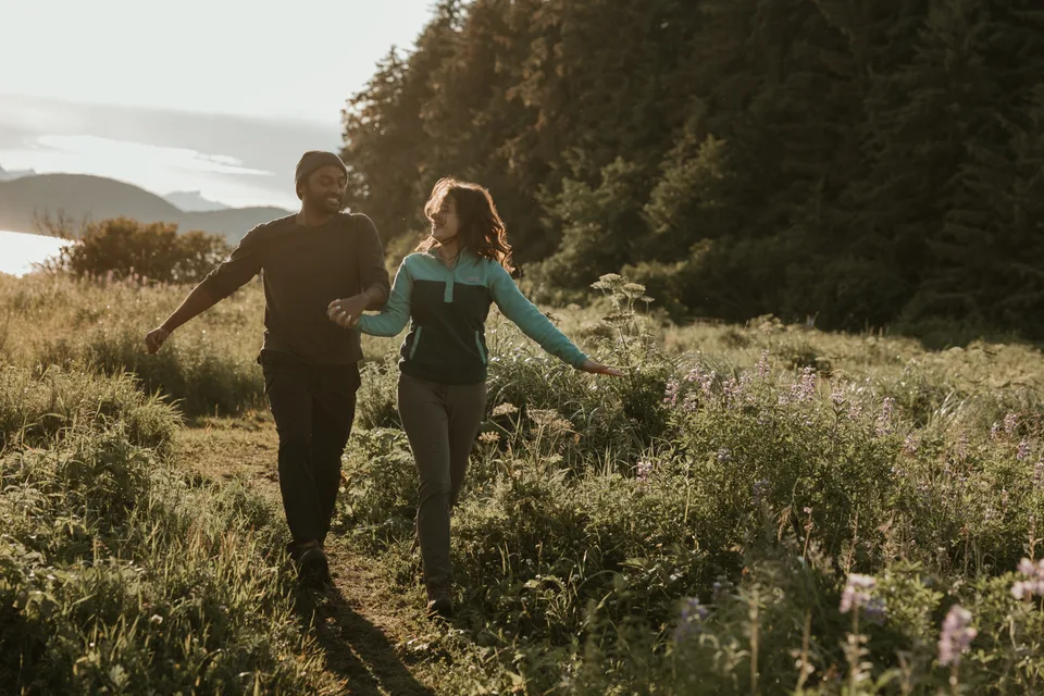 Brianna and Ivan walking through a sunlit meadow trail.